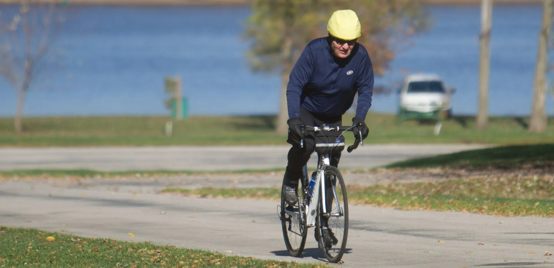 A man wearing a yellow helmet is riding a bike on a path.