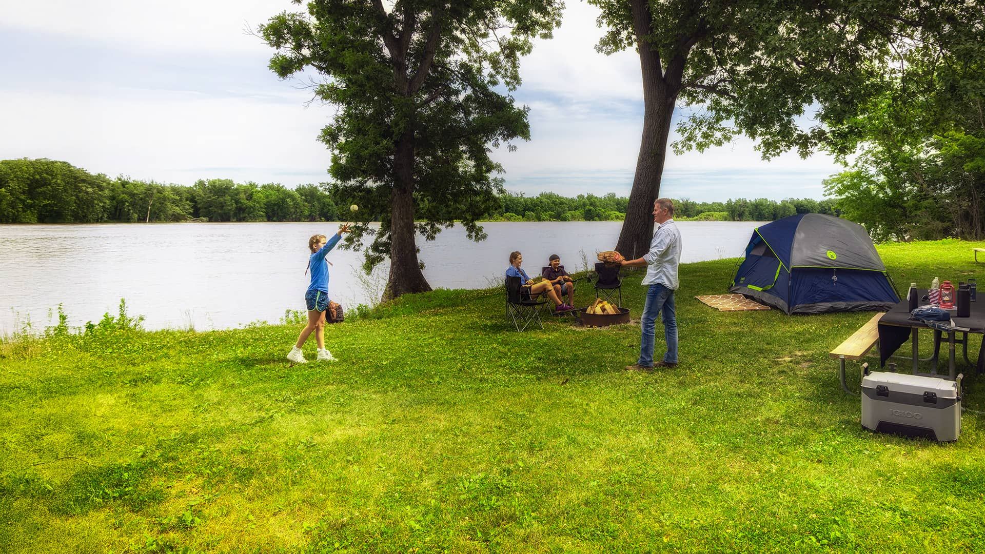 Family playing catch at campsite along the lake