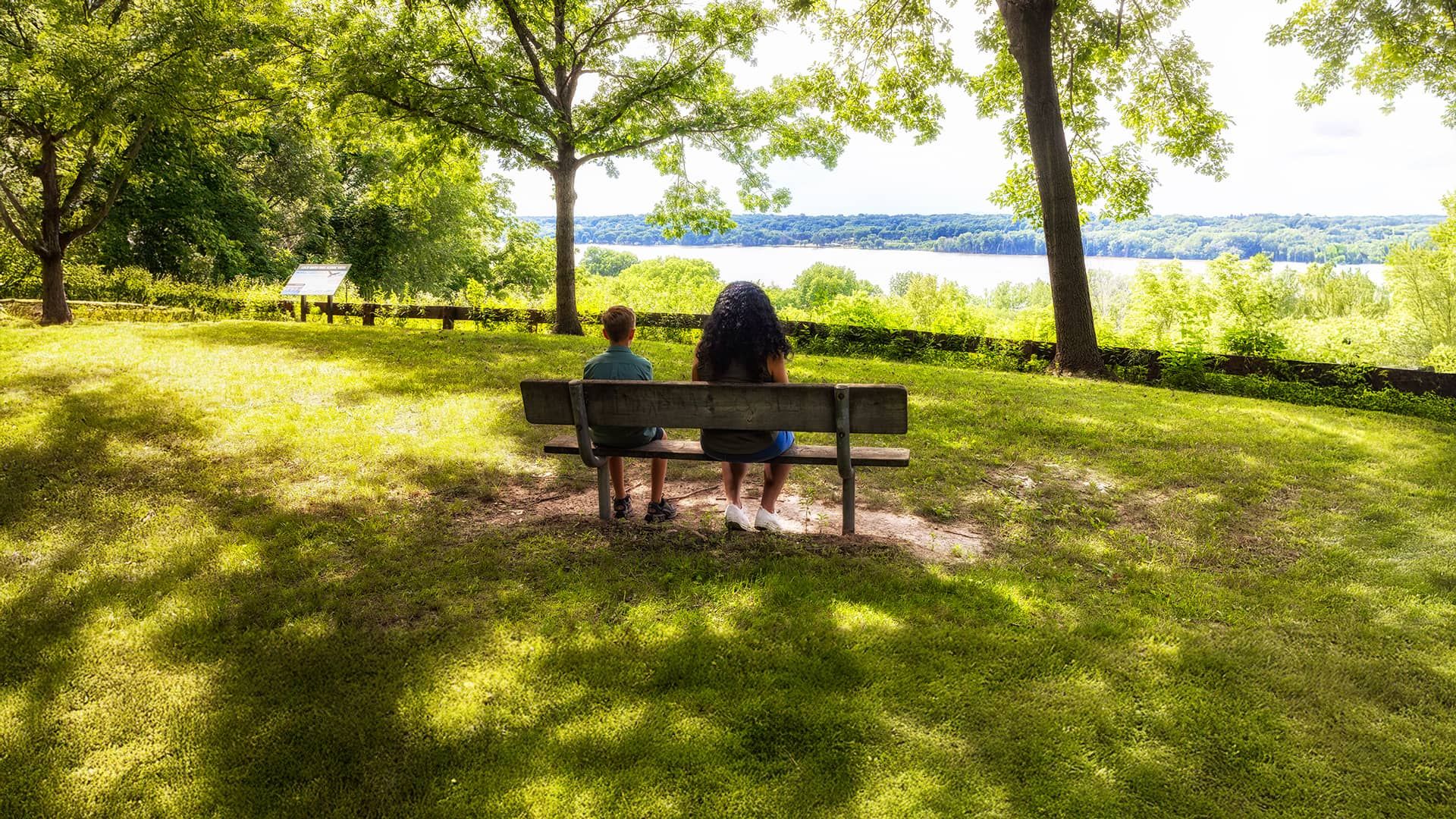 Two people sitting on a bench overlooking a lake