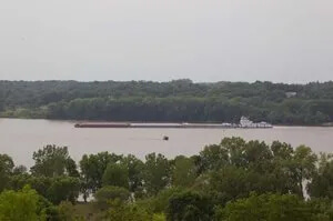 A large body of water surrounded by trees and a barge.