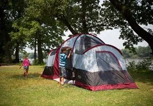 A boy and a girl are standing in front of a tent.