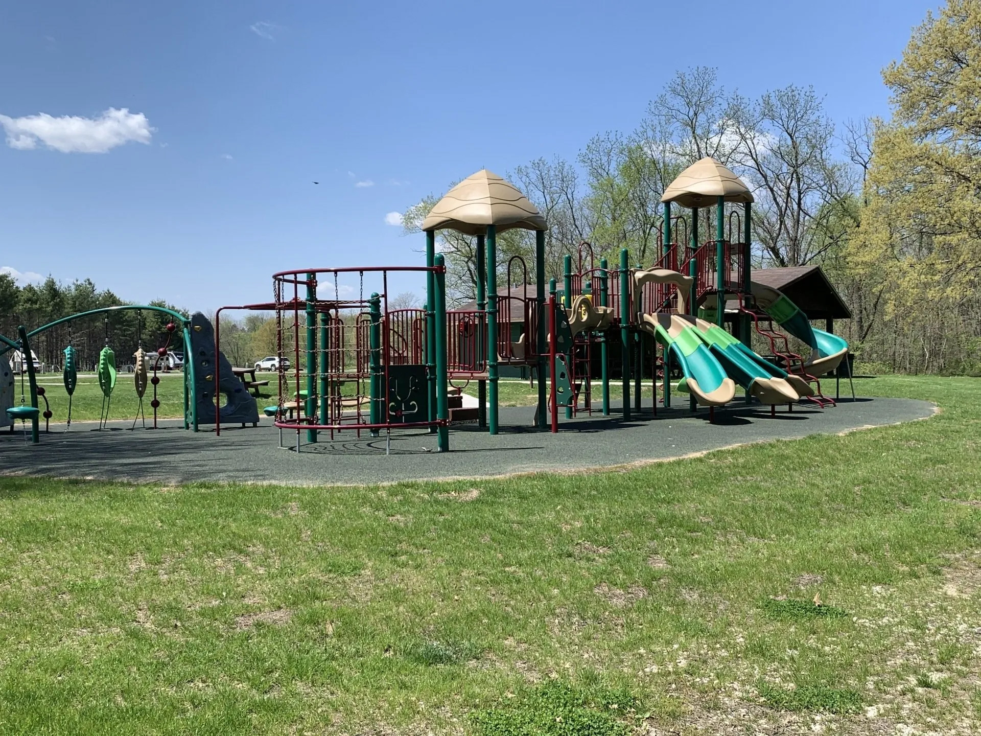 A large playground in a park with a blue sky in the background.
