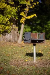 A grill is sitting in the middle of a grassy field.