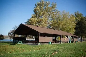 A picnic shelter in a park with a lake in the background.
