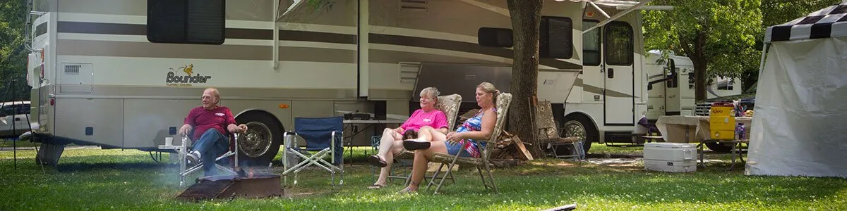 A group of people are sitting in chairs in front of a RV.