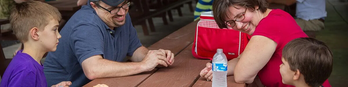 A family is sitting at a picnic table with a bottle of water.
